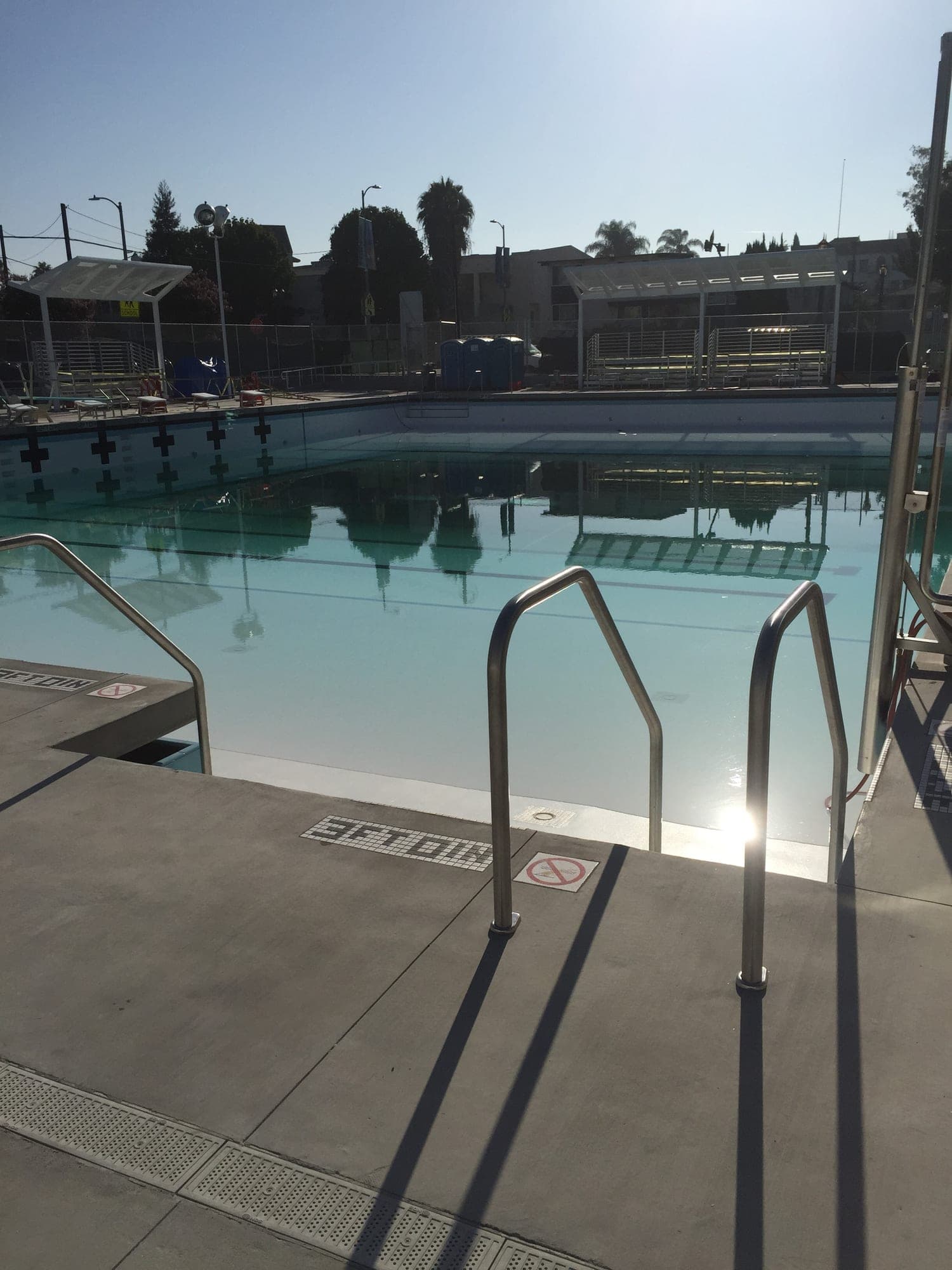 Finished commercial swimming pool with concrete deck, handrails and lane markings