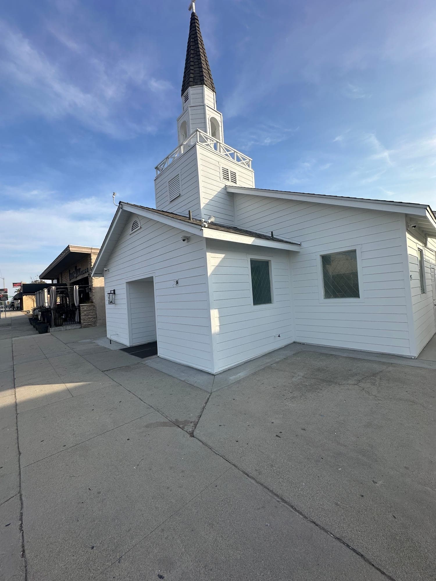 Finished white board-and-batten church with classic steeple